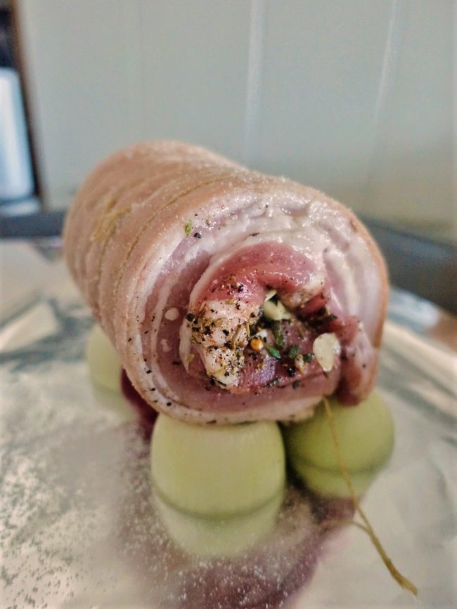 A snug porchetta roll, balanced on onions.